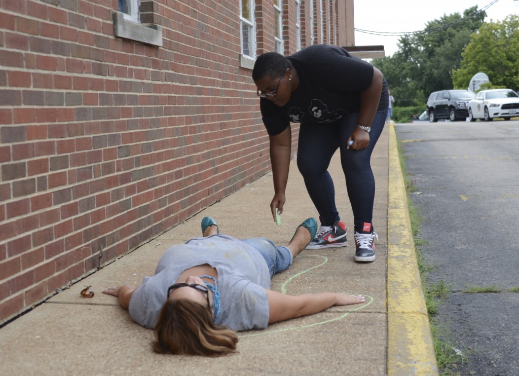 Participant draws a chalk body outline at the rally site after the march. Photo by ELLEN DAVIDSON