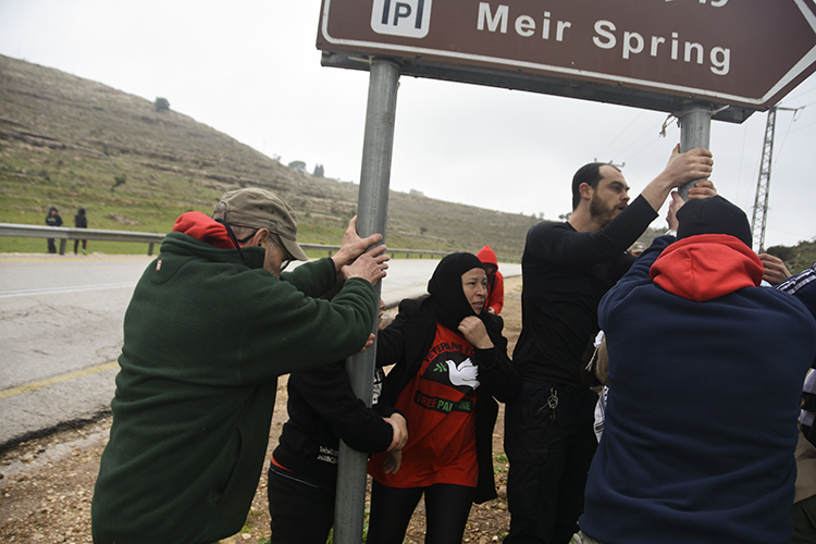 Shaking the sign for the spring, which Israeli settlers have claimed. PHOTO: ELLEN DAVIDSON